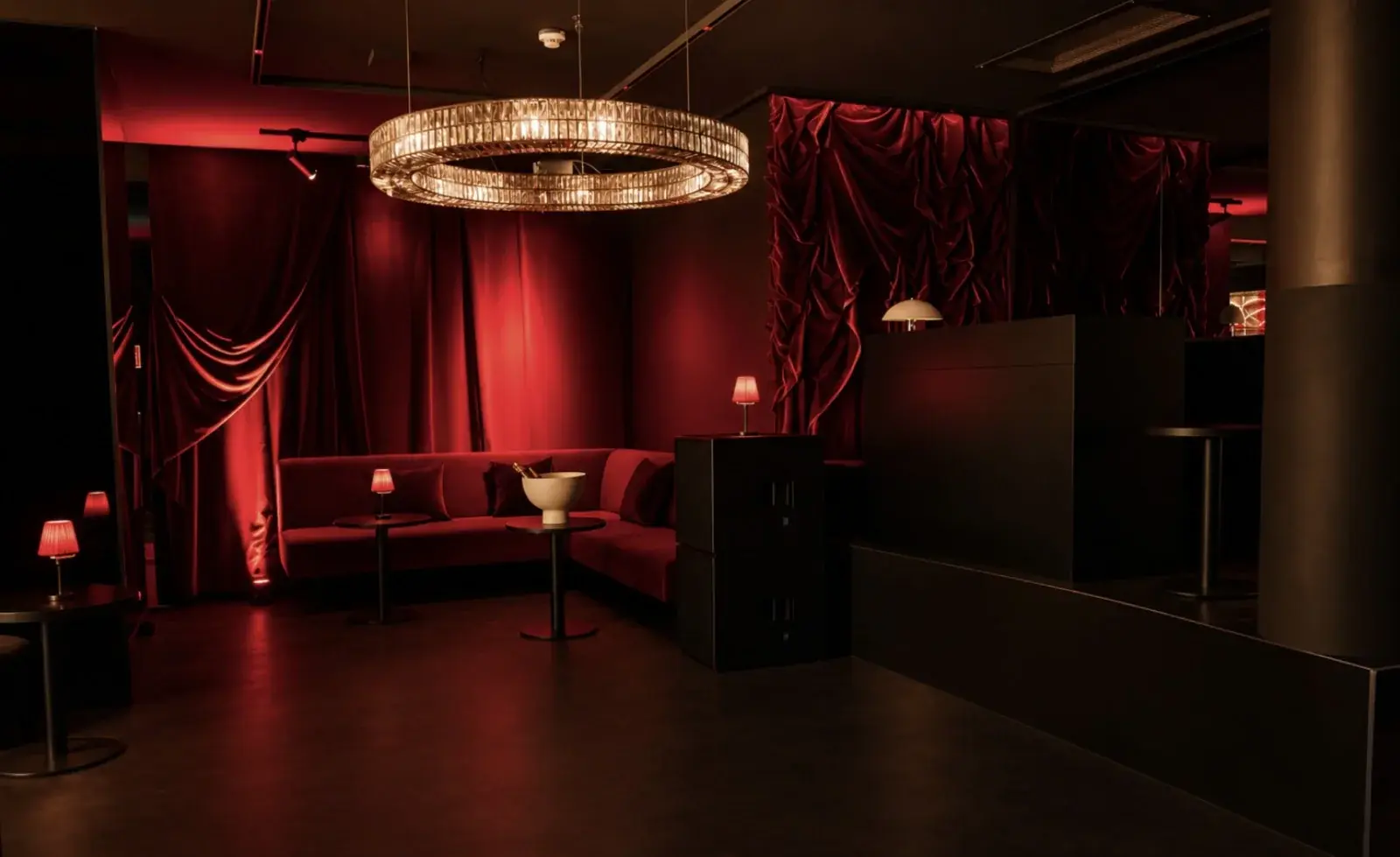 VIP-Lounge mit rotem Samtsofa, Samtvorhängen und Kristall-Kronleuchter.